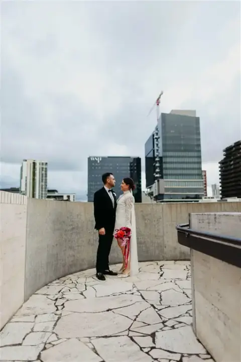 Amy's makeup by Juliana Cruz catching the golden hour light as the couple pose on The Calile's rooftop with Brisbane's skyline in the background
