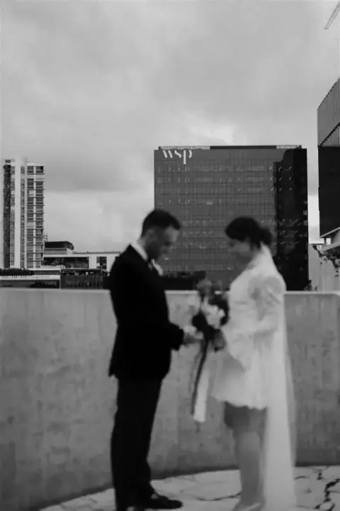 Christian twirls Amy on the rooftop as the rain begins to fall, their joy undiminished by the weather
